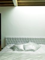 Modern white bedroom with upholstered headboard and soft furnishings 