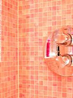 Detail of shower fitting on pink mosaic tiled walls