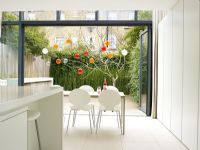 Modern kitchen diner with patio doors open to garden 