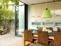 Modern kitchen diner with open doors to garden 