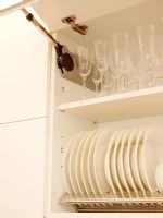 Detail of modern kitchen cupboard open showing plates and glasses 