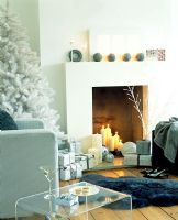 Modern living room with Christmas tree and lit candles in fireplace