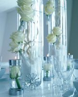 Lit candles, flowers in vases and Christmas decorations on table