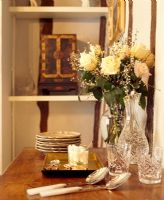 Vase of flowers, glasses and serving spoons on sideboard in dining room