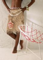 Woman in a grass skirt leaning against a wall