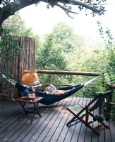 Man lying in hammock reading book