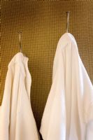 His and Hers White Bathrobes Hanging from Wall Hooks