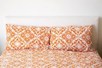 Bed with Orange Print Sheets and Pillows
