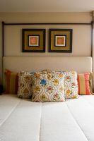 Symmetrical detail of decorative pillows on bed.