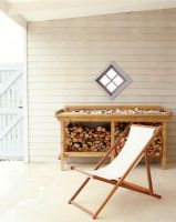 Folding chair on a patio with a wood pile