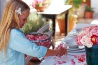Girl arranging flower petals on dining table
