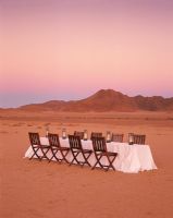 Dining table with empty chairs in desert