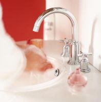 Person washing hands in bathroom sink, focus on tap