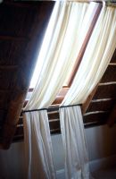 Window in a thatched roof with curtains