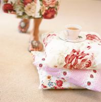 Low section of woman and tea cup on stack of pillows