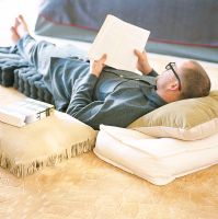 Man lying on cushions reading