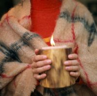 Person wrapped in a blanket holding a large candle
