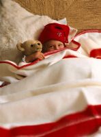 Child with a stuffed toy hiding under a blanket