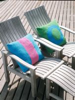 Two wooden beach chairs with colourful pillows