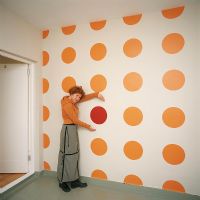 A woman next to a white wall with yellow polka dots