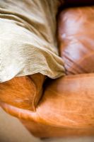 Detail of leather couch arm with throw blanket.