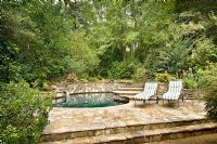 View of pool with stone patio and greenery