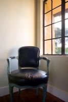 Worn antique leather chair in corner next to window