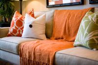 Comfortable sofa with orange throw blanket and cushions