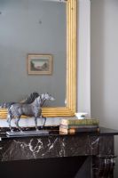 Horse statue and books on marble mantelpiece