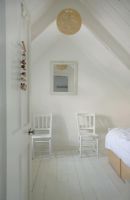 White attic bedroom with two chairs