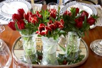 Dinning table detail of three cut glass vases with red tulips