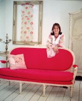 Woman leaning on a bright red vintage sofa