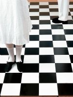 Low section of man and woman standing on checked floor