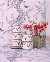 Stack of cup and saucers beside flower vase