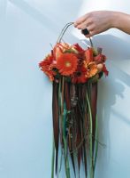 A person hanging a bouquet of flowers on the wall