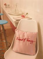 An embroidered pink pillow on a chair