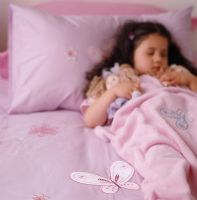 Girl sleeping on bed with doll