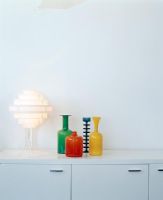 Lamp beside coloured glassware on side table