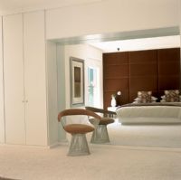 A reflection in the mirror of a contemporary white and brown bedroom