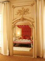 View of a four poster bed reflected in a full length mirror