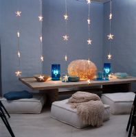 Low dining table with cushions and strands of star shaped lights