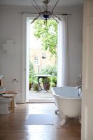 Roll top bath in bathroom with stripped floors