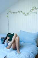 Woman reclining on bed reading book