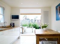 Contemporary white kitchen with oak kitchen worktop and porcelain tiled flooring