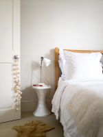 Contemporary white bedroom with Tam Tam stool used as bedside table