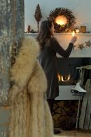 Woman lighting candles on mantelpiece 