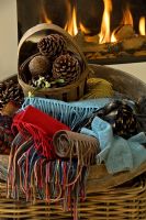Basket of scarves and pine cones by fire
