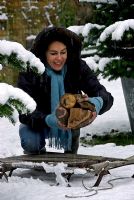 Woman putting logs on sledge in snowy garden