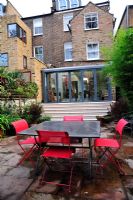Modern table and chairs in paved garden 