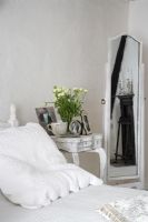 across white bed to white bedside table with mirror large depth of field